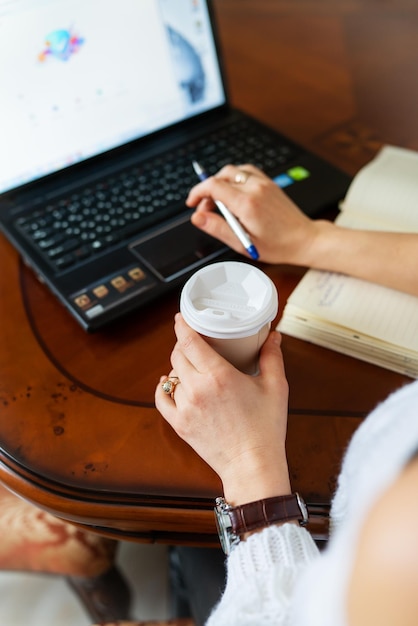 Young woman working on a laptop at home at the table online learning on PC elearning Work online remote work Closeup view over the shoulder