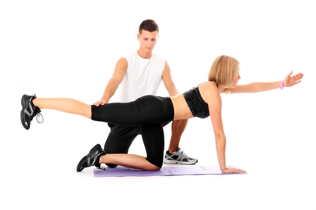 a young woman working out with her personal trainer over white background