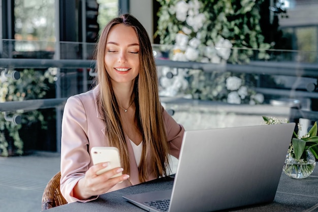 Young woman working remotely from a cafe using laptop smiling