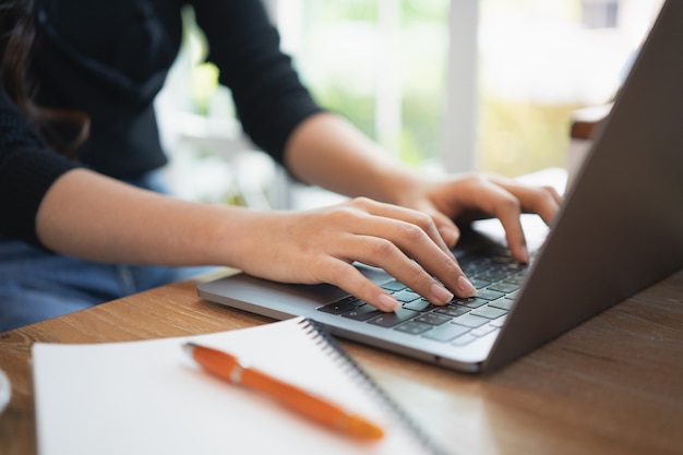 Young woman working with laptop on the wood table in the cafe