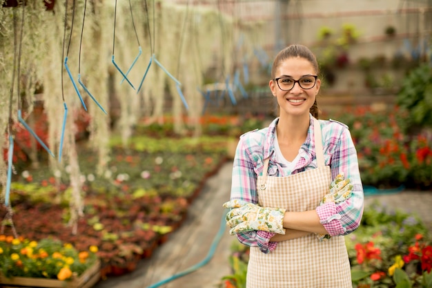 Young woman working with spring flowers in the greenhouse