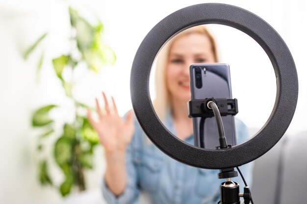 A young woman works, conducts live broadcasts from home by the Internet. female talks, leads a lesson, blog online. female blogger writes a blog issue using round lamp.