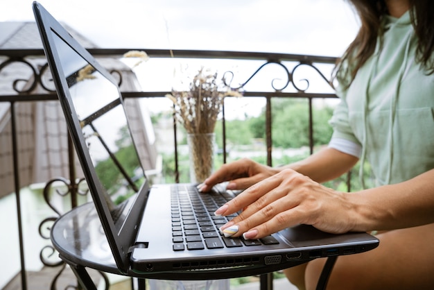 Young woman works at a laptop on the terrace remote work concept