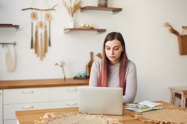 Young woman works remotely on laptop at home, distance education. Freelance work. Teaching students online.