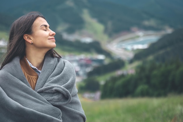 A young woman wrapped in a blanket in the mountains