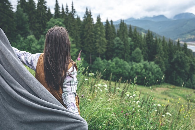 A young woman wrapped in a blanket in the mountains