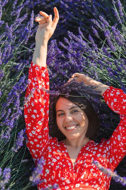 A young woman in a wreath on her head lies on a lavender field