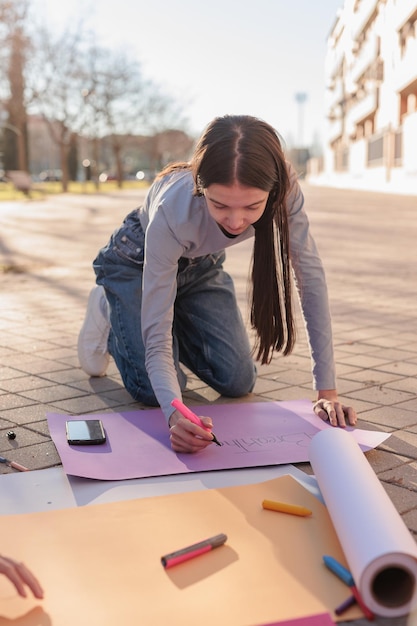 Young woman writing on banner outdoors