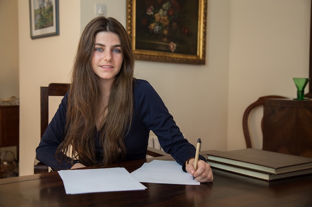 Young woman writing on a blank sheet with a pen.