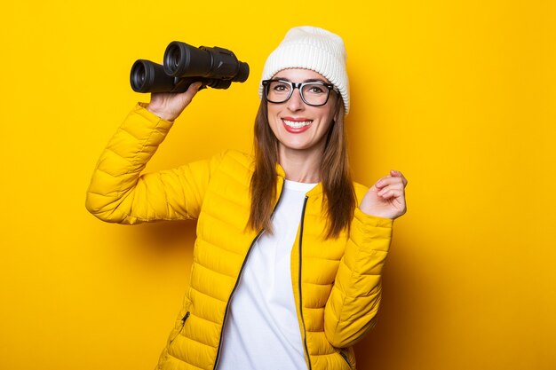 Young woman in yellow jacket holding binoculars