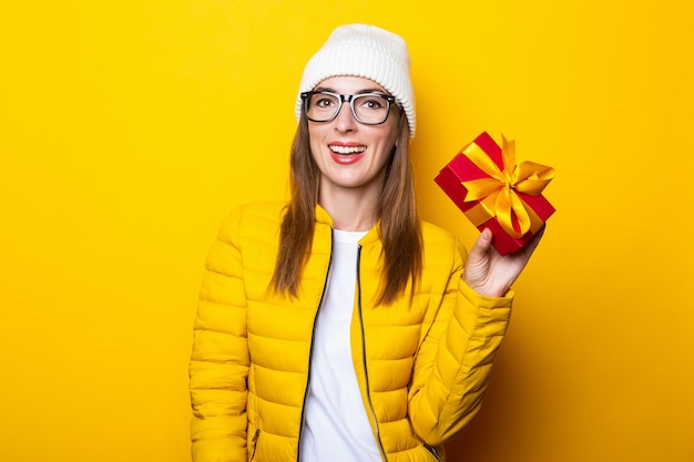 Young woman in yellow jacket holding gift