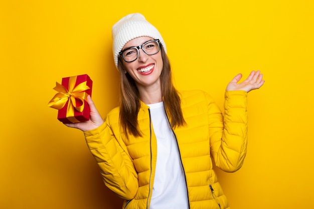 Young woman in yellow jacket holding gift