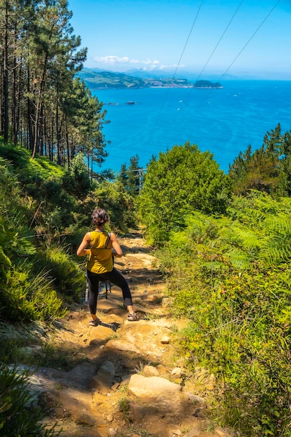 A young woman in a yellow shirt on the trail going down to the town of Orio Guipuzcoa Basque Country