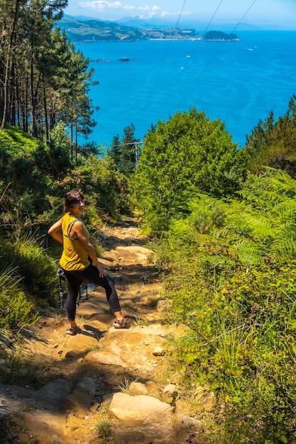 A young woman in a yellow shirt on the trail going down to the town of Orio Guipuzcoa Basque Country