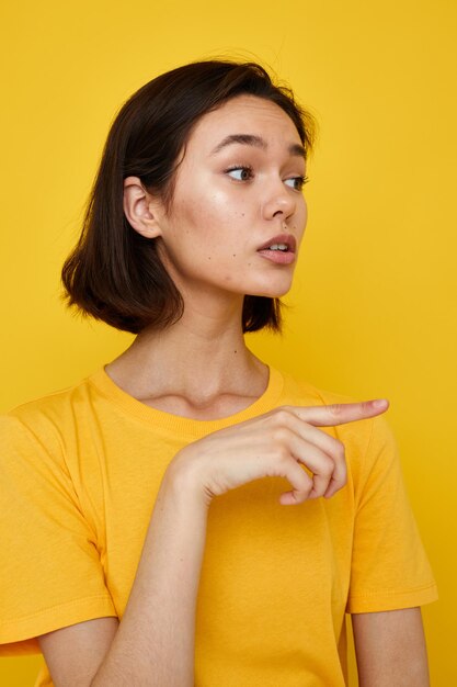 Young woman in yellow tshirt posing fashion yellow background