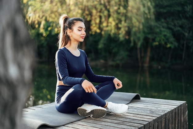 Young woman on a yoga mat relaxing outdoors