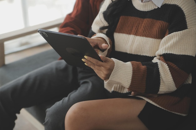 Young woman and young man using laptop while sitting by the sofa at home