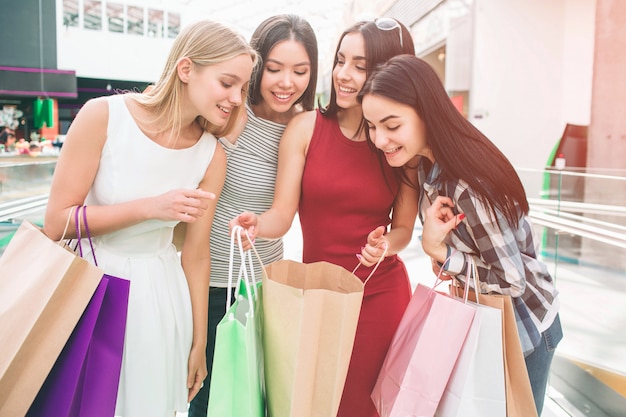 Young women are standing together and looking into one bag