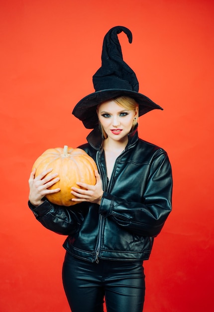 Young women in black witch halloween costumes on party over red background Emotional young women in