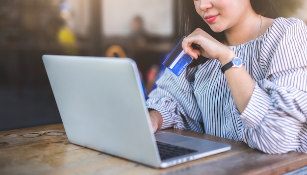 Young women holding credit card and using laptop