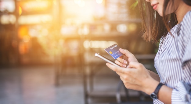 Young women holding credit card and using smartphone