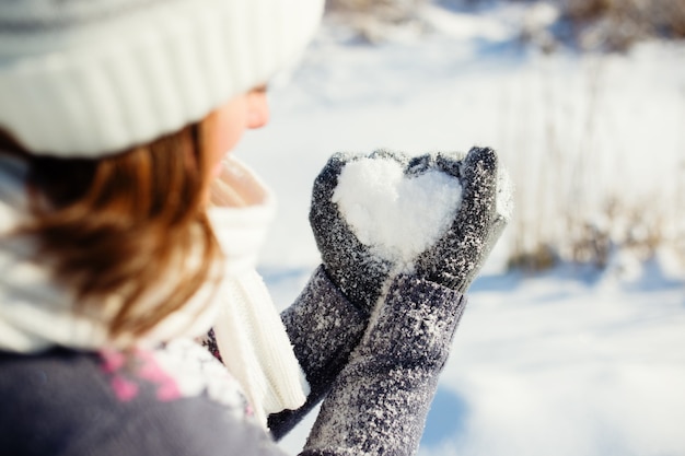 Young women holding heart shaped snow in hands