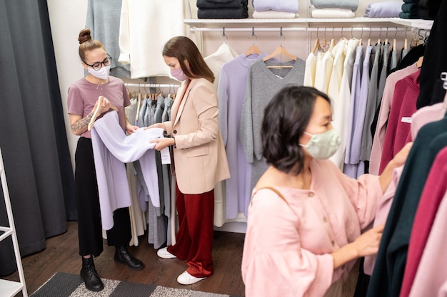 Young women in protective masks doing shopping in store during pandemic