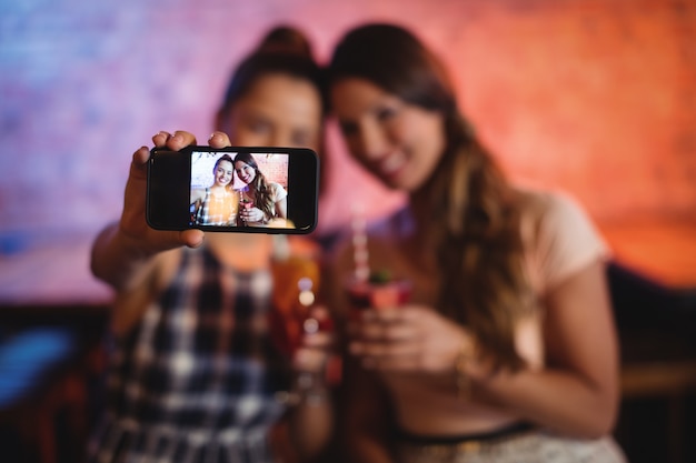 Young women taking a selfie while having cocktail drinks