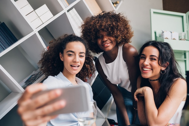 young women taking selfie with smartphone and having fun in modern location 