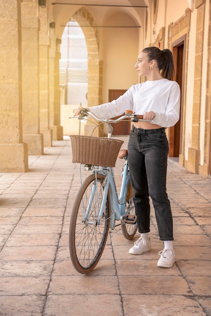 Young women with bicycle looking away in a small town