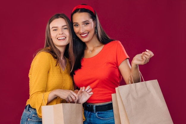 Young women with shopping bags on a red background