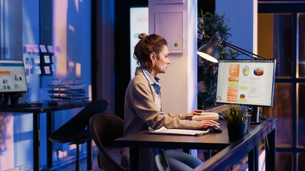 Young worker analyzing documents with statistics in corporate office, working to create financial business graphs report. Woman planning analytics project to increase profit. Tripod shot.