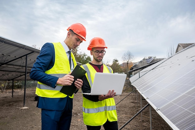 Young worker in overalls with boss in overalls looking at newly installed solar panels