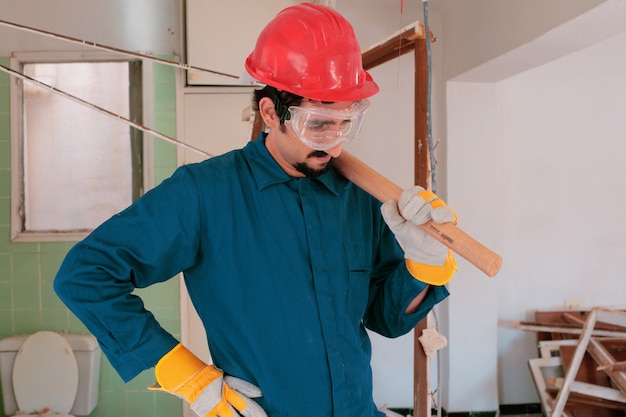 young worker with a red protection helmet and wearing a blue boiler suit. demolition concept