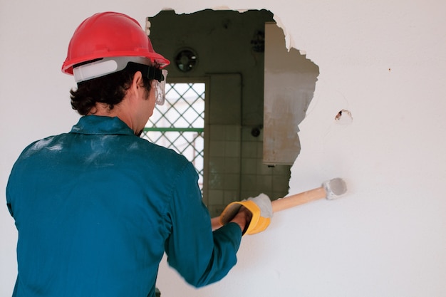 young worker with a red protection helmet and wearing a blue boiler suit. demolition concept