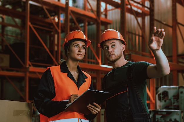 Young Workers in Hardhats Talking in Warehouse