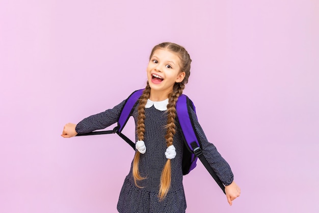 A young young schoolgirl in a polka dot dress and with long pigtails is very happy and smiling