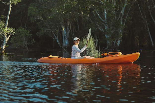 Younger asian woman sailing sea kayak in fresh water lagoon