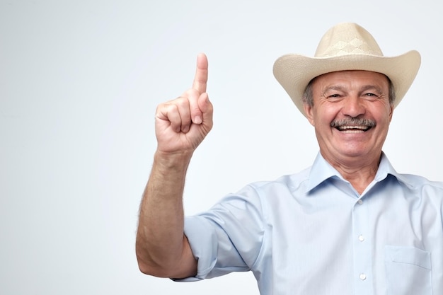 Your advertising here Studio portrait of handsome senior man in blue shirt and cowboy hat showing copy space