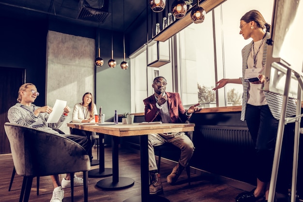 Do your best. Handsome dark-skinned man actively gesticulating while talking with his coworker