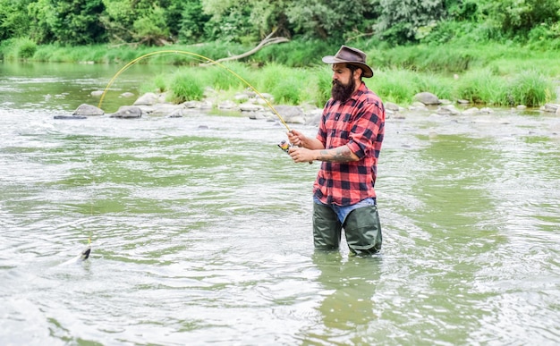 Your Favourite hobby bearded fisher in water hobby and sport activity fisherman show fishing technique use rod mature man fly fishing man catching fish summer weekend Happy fly fishing