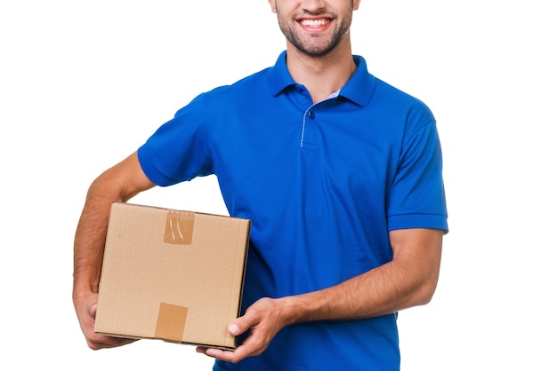 Your package is in safe hands. Cropped image of young courier holding a cardboard box and smiling while standing against white background