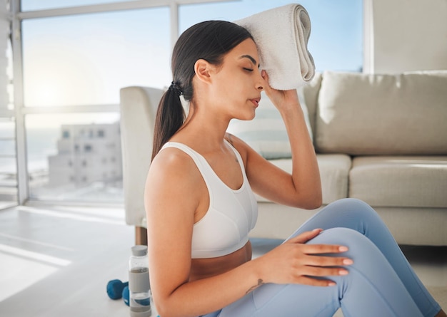 Youre going to want to give up, but dont. Shot of a sporty young woman wiping her forehead with a towel while exercising at home.