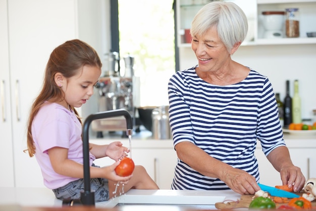 Youre a great little helper Cropped shot of a grandmother washing vegetables with her grandchild in a kitchen