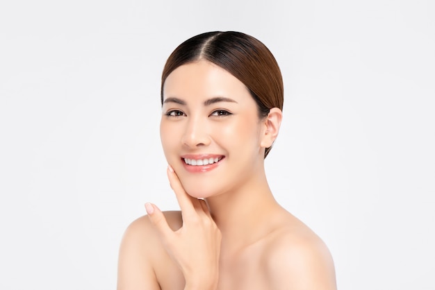 Youthful pretty Asian woman with hand touching face on white wall for beauty and skin care concepts