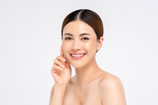 Youthful smiling pretty Asian woman with hand touching face on white background