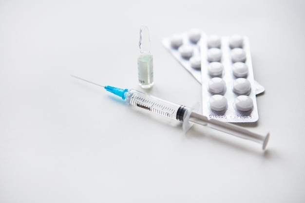 yringe, vaccine, pills, medical mask on a white table