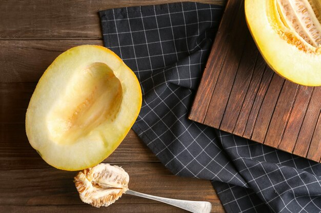 Yummy half of melon and spoon with seeds on wooden table