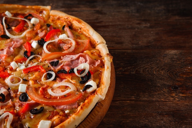 Yummy pizza sliced on rustic wooden table background with free space. Junk food, bad habits. Italian traditional cuisine.