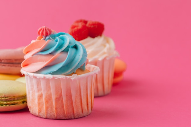 Yummy sweet cupcakes on light pink background